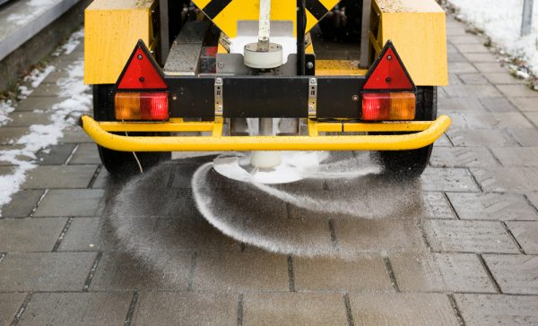 Salt on sidewalk A machine is sprinkling salt on a sidewalk